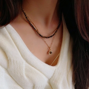 Double-layer tiger eye stone necklace with gold pendant on a knitted sweater