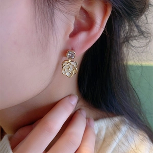 Vue rapprochée de boucle d'oreille camélia français avec pétale blanc et zircon carré