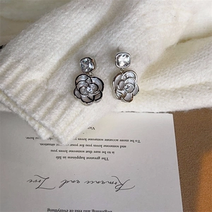 Vue détaillée de boucles d'oreilles camélia argentées avec zircon carré et pétales ajourés