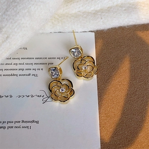Détail macro de boucles d'oreilles camélia dorées avec zircons et style français élégant