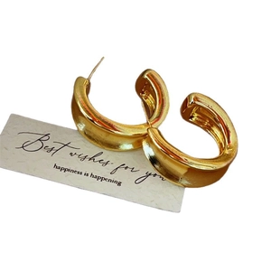 Chunky gold-plated C-shaped hoop earrings with a high-gloss finish on a white gift card