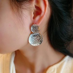 Minimalist hammered silver double circle drop earrings worn by a female model
