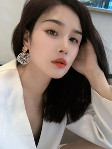 Detail of oversized gold and silver contrast hollow statement earrings on a female model