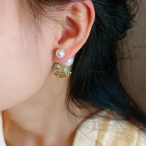 Elegant rocking horse pearl earrings featuring light blue enamel and golden details