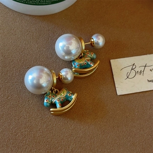 Detail of pearl rocking horse earrings with blue enamel finish on brown velvet background