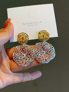 Detail view of two-tone openwork earrings with unique abstract metal texture
