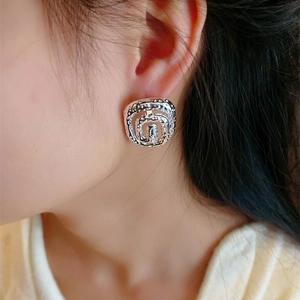 Lava texture silver spiral stud earrings with elegant square silhouette on female model