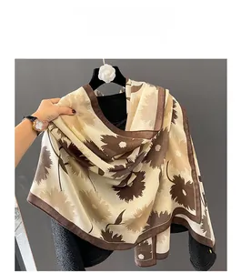 Détail d'une écharpe en coton et lin avec motif floral et bordure marron raffinée