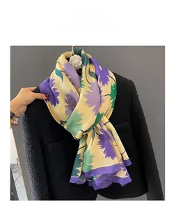 Détail de l'écharpe en lin à fleurs avec bordure violette sur une veste en tweed noir