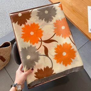 Détail de l'écharpe en coton et lin beige avec imprimé floral et bordures contrastées