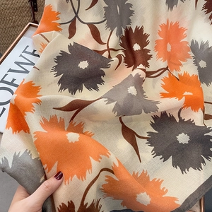 Détail du châle en coton et lin avec des motifs floraux artistiques en orange et gris