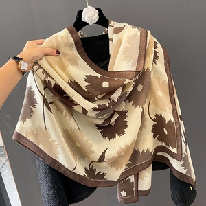 Détail de texture d'une écharpe en coton et lin avec motifs floraux marron sur fond beige