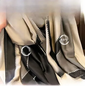 Close-up of silk-like scarf featuring black and champagne geometric patterns and textures