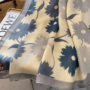 Détail macro de l'imprimé floral et de la texture douce du châle en lin et coton beige