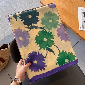 Détail d'une écharpe en coton et lin à motifs floraux verts et violets sur fond bois
