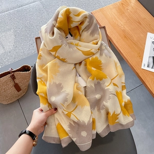 Détail du grand motif floral jaune sur une écharpe en coton et lin de couleur crème doux