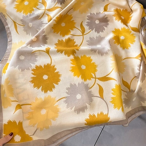 Détail d'une écharpe en coton et lin avec imprimé floral jaune et bordure cousue
