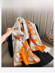 Détail du motif camélia sur une élégante écharpe en soie avec épissure orange et blanc