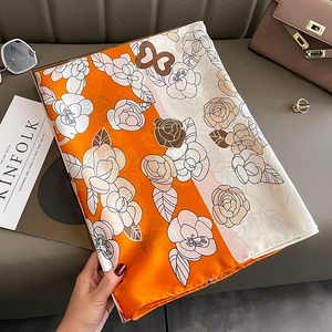 Détail de la texture en soie douce et du motif rose sur un foulard en soie orange