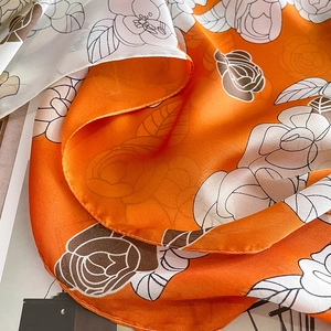 Détail d'un foulard en soie doux avec motif floral de camélia orange et beige élégant