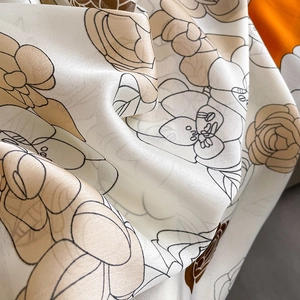 Gros plan détaillé d'un foulard en soie à imprimé camélia montrant la texture du sergé