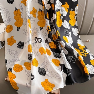 Détail d'un foulard en soie aux motifs de camélias noirs, blancs et dorés élégants