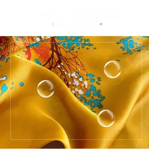 Detailed close-up of bright yellow faux silk scarf with artistic tree and leaf patterns