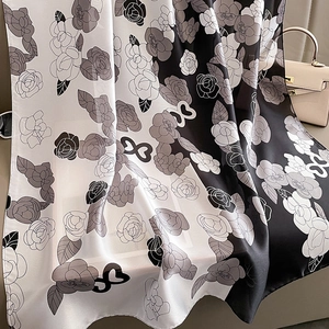 Détail d'un foulard en soie avec motifs camélia et élégante texture patchwork noir et blanc