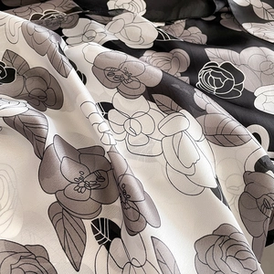 Détail de l'imprimé floral camélia sur une texture de foulard en soie brillante