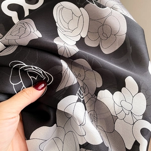 Gros plan du foulard à motif camélia montrant la texture soyeuse et le drapé du tissu