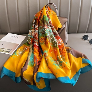 Silk-like square scarf with yellow landscape print draped elegantly over a handbag