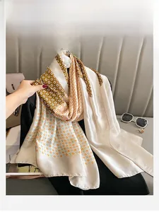 Detail of luxury silk-like scarf with geometric patterns and dots on a beige background