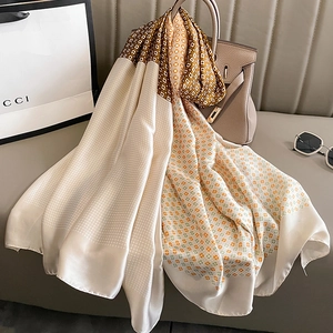 Elegant silk-like scarf with vintage geometric patterns draped over a stylish handbag