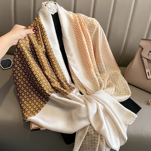 Silk-feel geometric scarf with orange and brown patterns draped over a luxury handbag