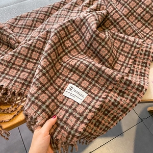 Détail d'une écharpe à carreaux vintage avec franges et étiquette tissée sur tissu cachemire