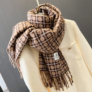 Détail d'une écharpe à carreaux marron avec franges sur un manteau blanc, texture douce