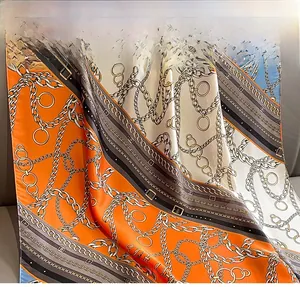 Close-up of silk-feel scarf with vintage chain patterns in orange and grey
