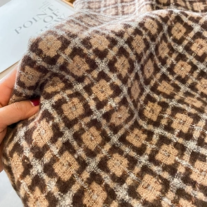 Gros plan du tissu d'écharpe à losanges avec fil doré et texture de tricot douce et chic