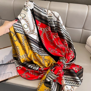 Detail of silk-satin scarf featuring horse chains and camellia brooch on a sofa