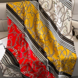 Close-up of silk-like satin scarf featuring vintage chain patterns and vibrant red-yellow tones