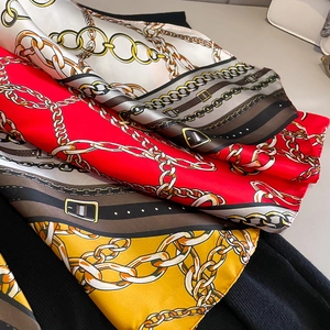 Detail of silk-like scarves featuring elegant golden chain and belt print patterns