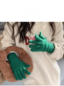 Detail of green knit fingerless gloves with ribbed cuffs and textile label on winter sweater