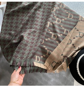 Close-up of houndstooth knit scarf featuring letter D patterns and tassel edge details