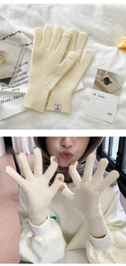 Detail of off-white waffle knit gloves with ribbed cuffs and a pink fabric label