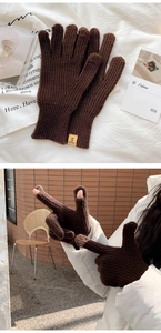 Detail of dark brown ribbed knit gloves featuring fingerless design and yellow label