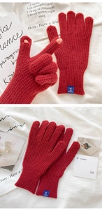 Macro detail of red knitted gloves with thumb slit for easy touchscreen operation