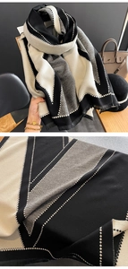 Detail of soft black, white, and grey patchwork scarf featuring fringes and geometric patterns