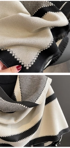 Detail of geometric knit scarf with fringe trim and tricolor zigzag pattern