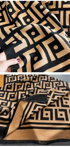 Dettaglio del motivo jacquard geometrico su una sciarpa spessa double-face nero e cammello