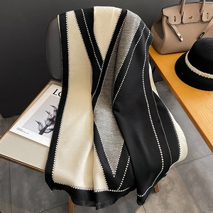 Black and gray cashmere-feel geometric scarf with white tassels on a stylish chair